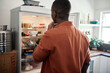 Young African man looking for something in his fridge