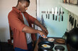 Young African man cracking eggs into a frypan for breakfast