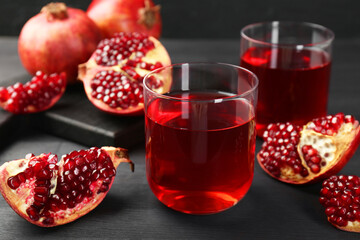 Tasty pomegranate juice in glasses and fresh fruits on black wooden table, closeup