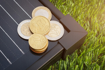 The heap of euro coins on the solar panel for energy generation. The European electricity generation price concept.