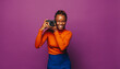 Vibrant african woman taking photos with a smile in purple studio
