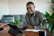 Smiling young African businessman working on a tablet at home