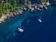 AERIAL: Two luxury sailboats are anchored in the breathtaking turquoise sea.
