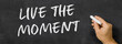  Text written on a blackboard -  Live the moment