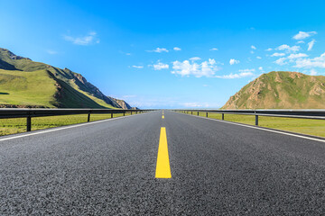 Straight asphalt highway road and mountains with sky clouds on a sunny day