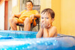 © kleberpicui - Happy child playing in inflatable home pool in summer. Active outdoor recreation.