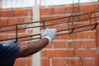Closeup of builder's hands lifting an iron column to make beams. Bricklayer working on house construction. Concept of architecture, industry, mason. 