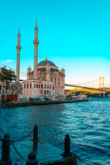 Wall Mural - A mosque with a blue sky in the background. Ortakoy Mosque, Besiktas Turkey. A mosque in Istanbul with the bridge in the background.
