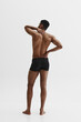 © master1305 - Rear view of young African-American shirtless man holding neck and back, standing in underwear isolated on white background. Health care. Concept of male beauty, sport, body care, health, fitness
