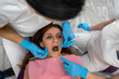 dentist with her assistant examines teeth of a young female patient at a dental appointment.