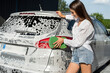 Young woman cleaning car use sponge with foap