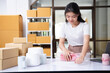 Small business entrepreneur woman packing product in mailing box for shipping from online store. Business online shipping and delivery concept.