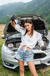 Young woman with wrenches trying to fix the car on the road.
