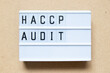 Lightbox with word HACCP (Hazard Analysis Critical Control Points) audit on wood background