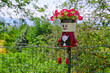 Cute flower pot character dressed as a man tied to a metal railing in a small Italian village, Langhe region, Piedmont, Italy