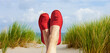 Damenbeine mit Roten Stoffschuhen am Strand
