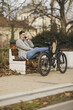 Man Sitting on a Bench Beside a Bicycle Talking on His Smartphone