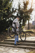 © milanmarkovic78 - Man Carrying Bicycle Up Stone Steps in Urban Park