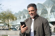 © Stock 4 You - 40s mature confident busy businessman entrepreneur using cellphone mobile phone for talking with family, business partners. Successful mid age man investor communicating on smartphone standing outdoor