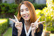 Friendly happy Asian office worker woman, showing V for victory hand gesture in smart casual corporate suit