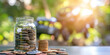 Accumulating Wealth for the Future: Coins in a Jar against a Blurred Natural Backdrop. Symbolic of Saving, Financial Planning in Peaceful Setting. Articles on Personal Finance, Sustainable Growth.