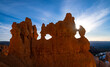 Silhouette of a rock formation in Bryce Canyon Nationalpark in Utah (USA). Bizarre shape with openings and unique outline backlit by the rising sun on a blue sky morning. Tourist attraction and sight.