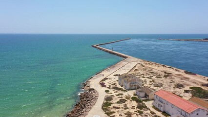 Wall Mural - An aerial view of the island of Ilha do Farol, located in the Algarve tourist region on Portugal's southern coast. View of the breakwater and the entrance to the bay.