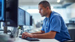 © Anna - Concentrated male nurse working on a computer in a hospital setting.