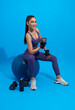 Healthy young asian sporty girl doing exercises with dumbbells isolated on blue fitness gym background.
