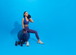 Asian beautiful happy woman holding towel and sitting on fit ball after exercise isolated on blue background. Woman healthy and exercising concept
