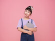 smiling young Asian girl crossed arms holding tablet computer isolated on pink background.