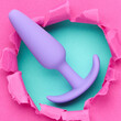 anal plug sex toy over hole in pink paper background