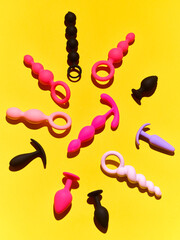 Wall Mural - Bright sex toys background. anal plugs and dildo over yellow paper backdrop