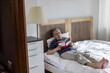 © Anna Berkut/Stocksy - senior retired asian man reading book in the bed at home