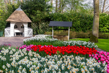 Canvas Print - Small white Pavilion and well in the middle of scenic Keukenhof gardens in the Netherlands.