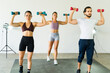 Full length view of three people lifting dumbbells in a gym class