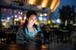 Woman use mobile phone at outdoor bar in the evening