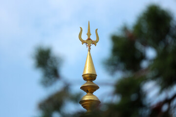 Wall Mural - Golden spire of a Hindu temple with a trident.