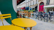 Paris, France, April 14th, 2024 Colorful sidewalk cafe setting with yellow tables and chairs on a European city street, suggesting urban lifestyle and al fresco dining concepts