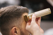 © Aleksandr - Professional hairdresser uses a hair clipper for fringing hair for a handsome barber man