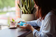 Woman sits at a cafe table with a coffee and a gift box wrapped in blue ribbon