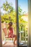 Fototapeta  - A woman lounging on the small cozy balcony, dressed in a summer outfit