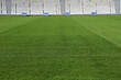 Sports stadium with green grass and spectator stands in the background. Soccer field, American football, baseball. Closeup of green stadium grass. Sports mockup. Sports background with copy space.