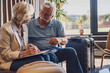Senior couple checking into a hotel. Elderly couple sitting in a hotel lobby filling in forms. Older people traveling.
