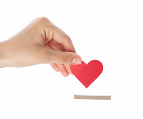 Wall Mural - Woman putting red heart into slot of donation box against white background, closeup