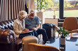 Senior couple checking into a hotel. Elderly couple sitting in a hotel lobby filling in forms. Older people traveling.