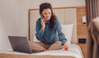 Businesswoman sitting on bed, using laptop. Woman working in hotel room. Business lady went to business trip and stayed at the hotel.