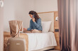Businesswoman sitting on bed, using laptop. Woman working in hotel room. Business lady went to business trip and stayed at the hotel.