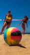 Beach Volleyball in the summer, volleyball closeup, blurred men, women in bikini background