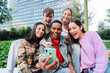 © Jose Calsina - Excited multiracial group of friends enjoying and smiling using a cellphone app. Diverse teenagers having fun watching content on the social media with a smartphone outdoors. Young people with phone